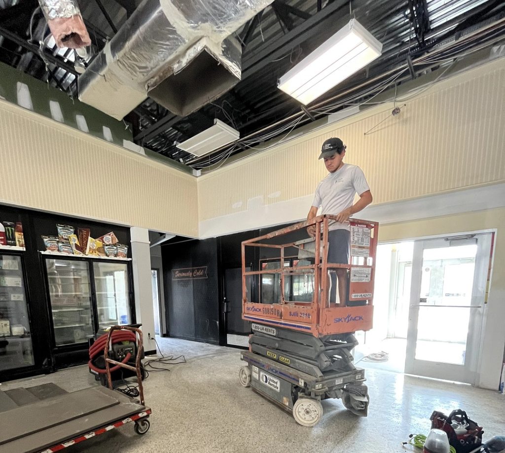 Man on a scissor lift preparing to clean air ducts at a retail business.