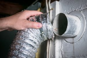 In Orlando, a man attaching the dryer vent pipe to the back of a dryer